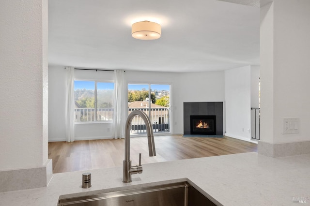 interior space featuring a tiled fireplace, sink, and light wood-type flooring