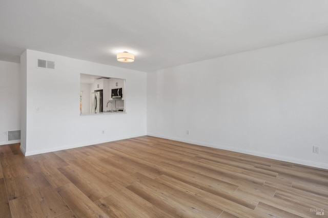 unfurnished room with sink and light hardwood / wood-style flooring