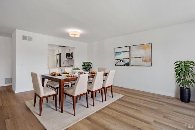 dining room with sink and light hardwood / wood-style flooring