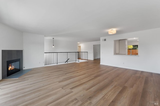 unfurnished living room with a tile fireplace and light hardwood / wood-style flooring