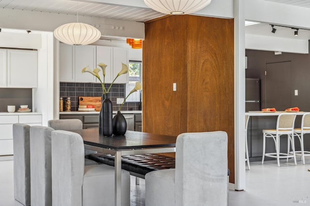 dining area with track lighting and beamed ceiling