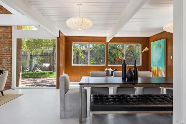 interior space with beam ceiling, concrete floors, and wood walls