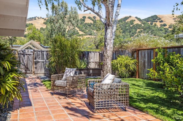 view of patio / terrace featuring an outdoor living space, fence, a mountain view, and a gate