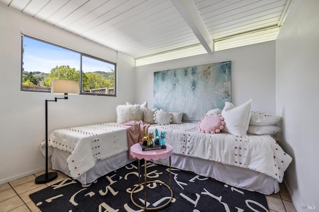 tiled bedroom featuring baseboards and beamed ceiling