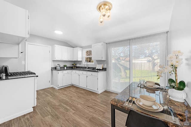 kitchen with white cabinetry, lofted ceiling, sink, and light hardwood / wood-style flooring