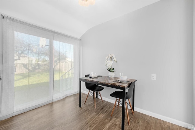 dining room with hardwood / wood-style floors, vaulted ceiling, and a wealth of natural light