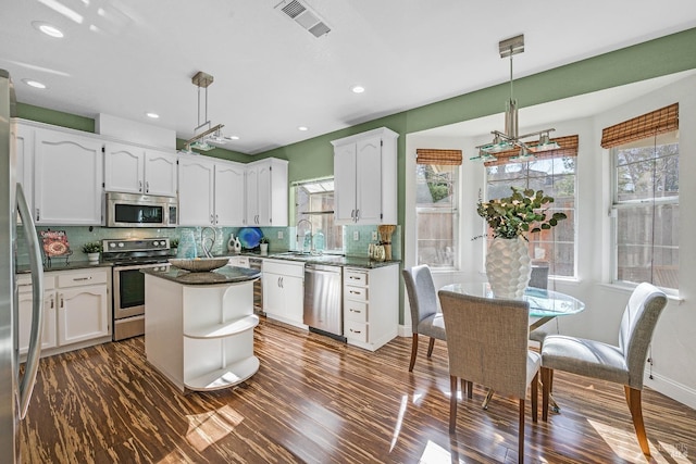 kitchen featuring hanging light fixtures, stainless steel appliances, sink, and white cabinets