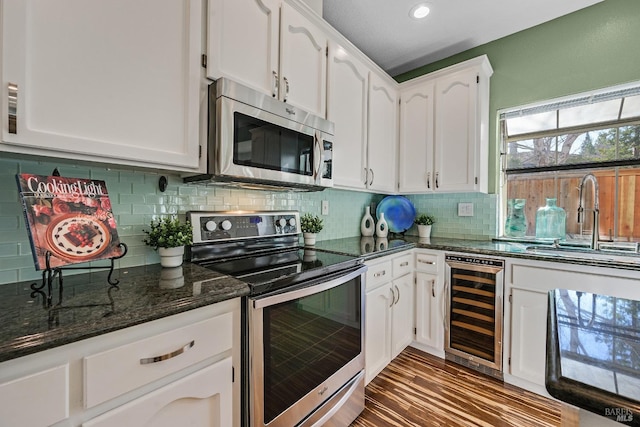 kitchen featuring sink, stainless steel appliances, beverage cooler, white cabinets, and dark stone counters