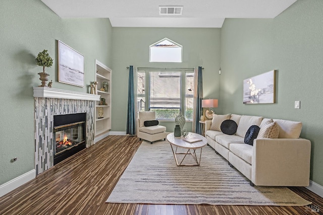 living room with a tile fireplace and dark wood-type flooring