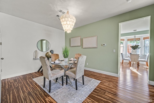 dining space with hardwood / wood-style flooring and a notable chandelier