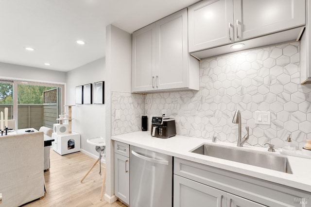 kitchen with sink, decorative backsplash, light hardwood / wood-style floors, and dishwasher