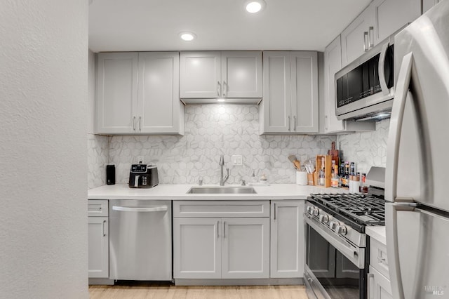 kitchen featuring tasteful backsplash, appliances with stainless steel finishes, light hardwood / wood-style floors, and sink