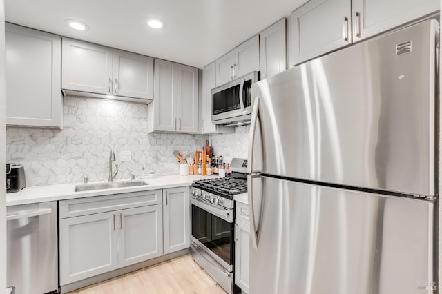 kitchen with sink, backsplash, stainless steel appliances, and light wood-type flooring