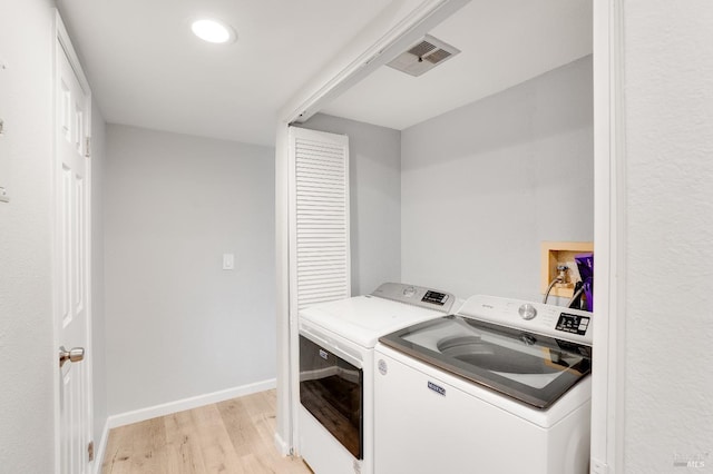 clothes washing area featuring washer and clothes dryer and light wood-type flooring