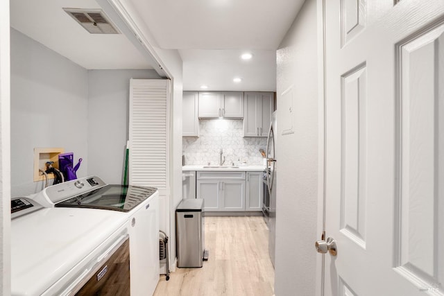 washroom featuring sink, light hardwood / wood-style flooring, and independent washer and dryer