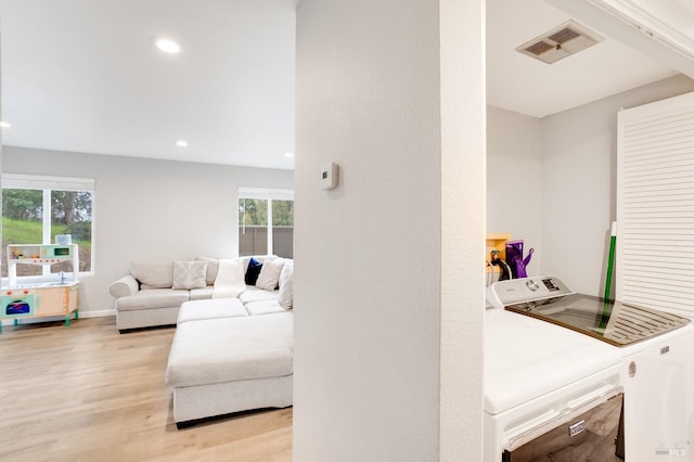 living room with washing machine and dryer and light wood-type flooring