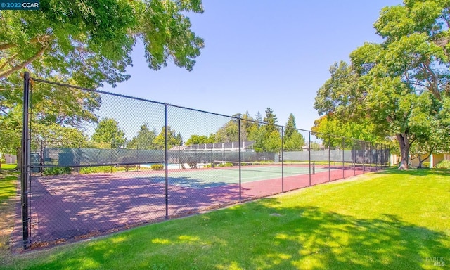 view of tennis court featuring a lawn