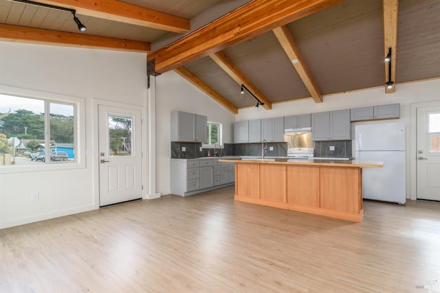 kitchen with lofted ceiling with beams, gray cabinetry, freestanding refrigerator, tasteful backsplash, and a center island with sink