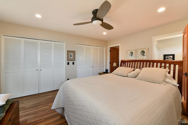 bedroom featuring two closets, dark wood-type flooring, and ceiling fan