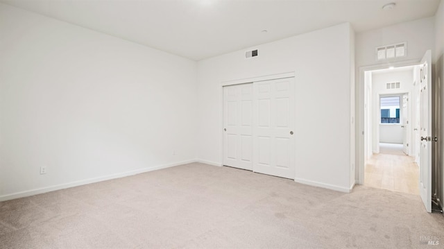 unfurnished bedroom featuring light carpet and a closet