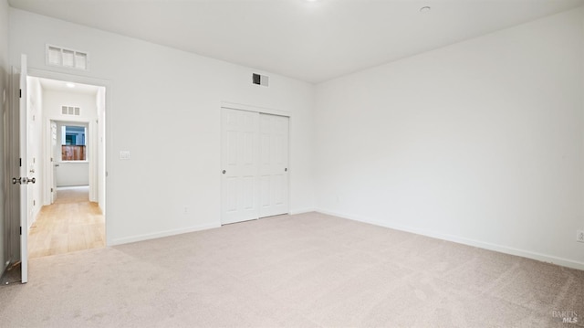 unfurnished bedroom with light colored carpet and a closet