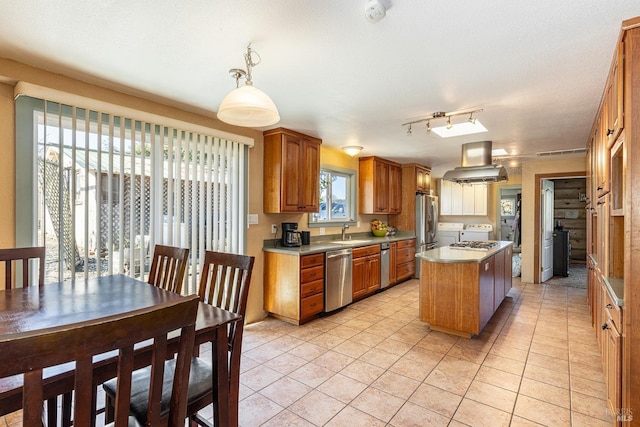 kitchen with sink, decorative light fixtures, island exhaust hood, stainless steel appliances, and a kitchen island with sink