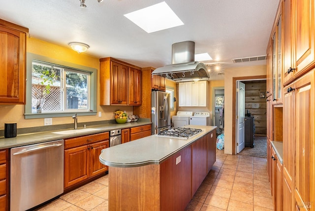 kitchen featuring sink, washer and clothes dryer, stainless steel appliances, a center island, and island exhaust hood