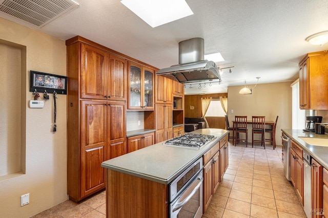 kitchen with sink, a kitchen island, pendant lighting, island exhaust hood, and stainless steel appliances