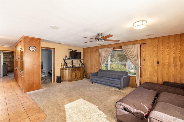 living room featuring ceiling fan, light tile patterned floors, and wood walls