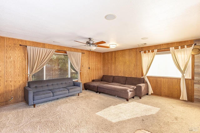 carpeted living room featuring ceiling fan and wooden walls