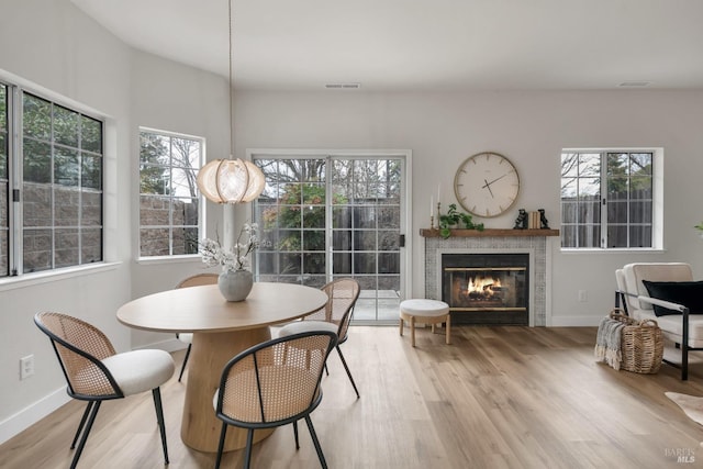 dining room featuring visible vents, a tile fireplace, baseboards, and wood finished floors