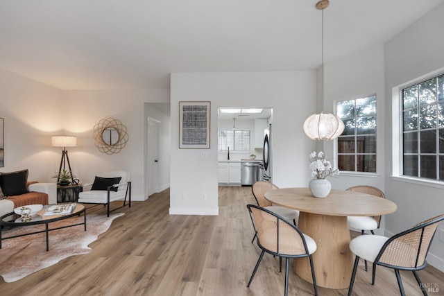 dining space with baseboards and light wood-style floors