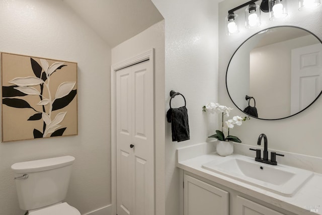 half bathroom featuring lofted ceiling, toilet, and vanity