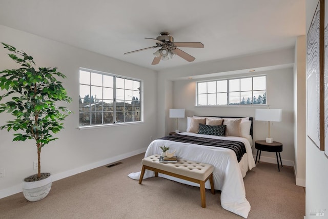 carpeted bedroom featuring a ceiling fan, multiple windows, baseboards, and visible vents