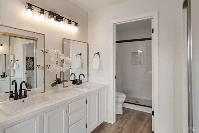 full bath featuring a sink, toilet, wood finished floors, and a shower stall