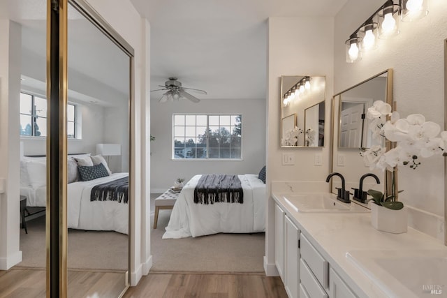 ensuite bathroom featuring wood finished floors, ensuite bath, a ceiling fan, and a sink