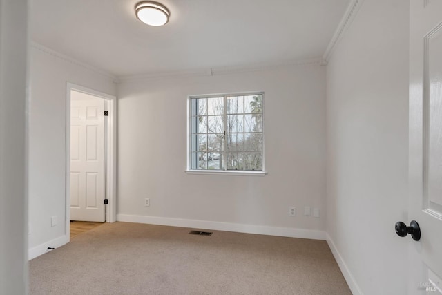 empty room with crown molding, carpet flooring, baseboards, and visible vents