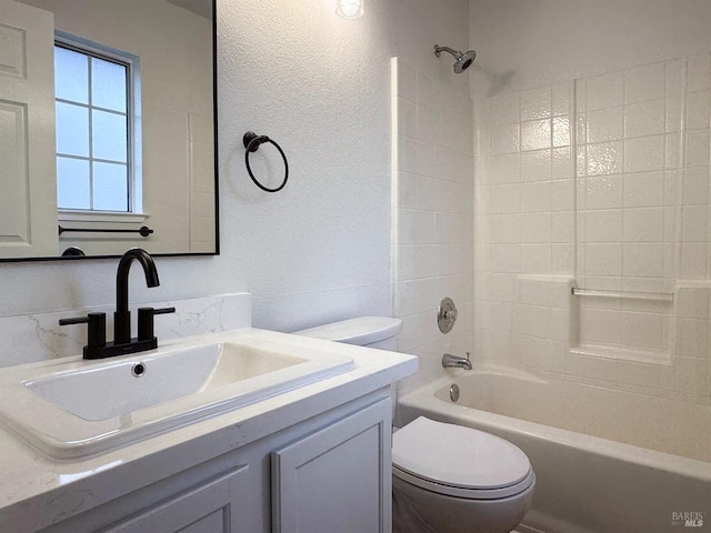 bathroom with vanity, shower / bathing tub combination, toilet, and a textured wall