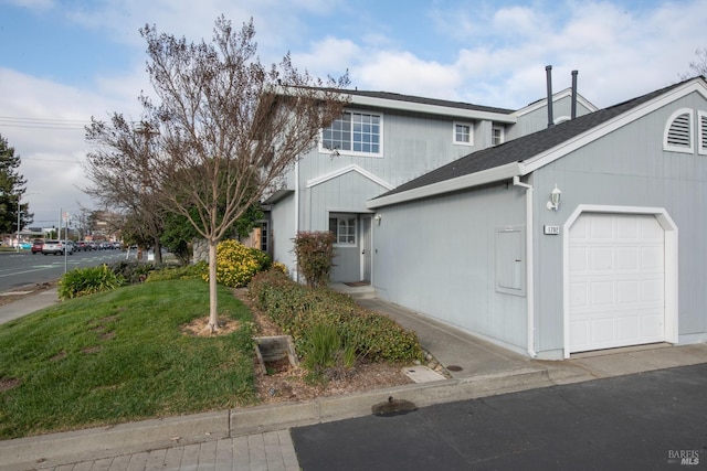 view of front facade with a garage, a front lawn, and roof with shingles