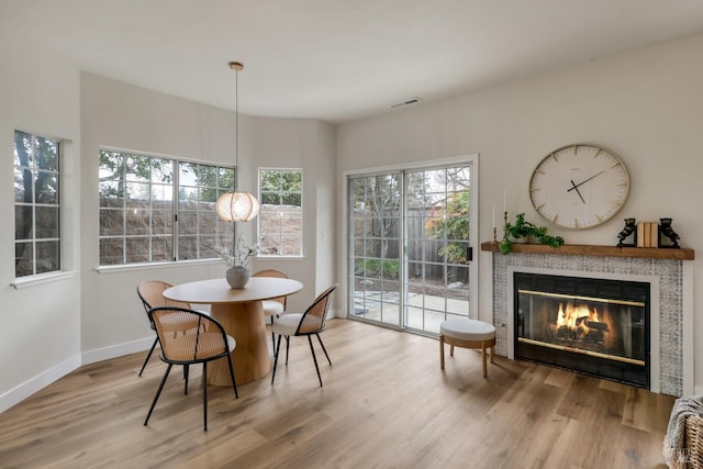 dining space featuring visible vents, a fireplace, baseboards, and wood finished floors