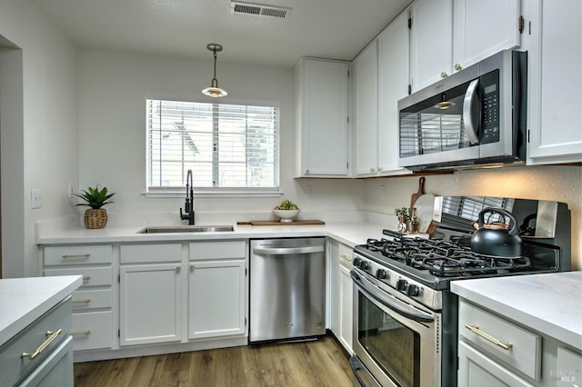 kitchen featuring light wood finished floors, visible vents, appliances with stainless steel finishes, white cabinets, and a sink