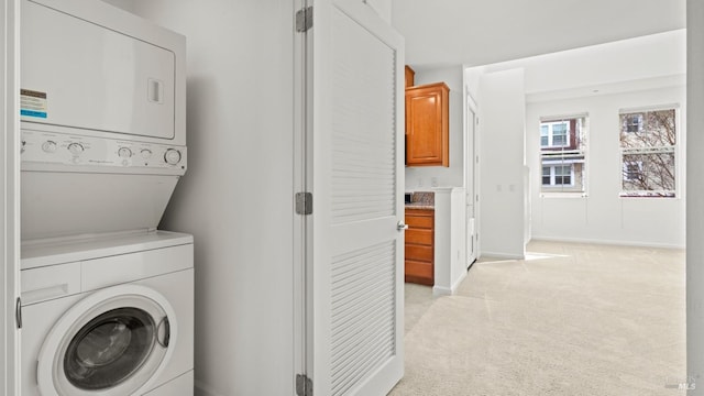 clothes washing area with stacked washer / drying machine and light colored carpet