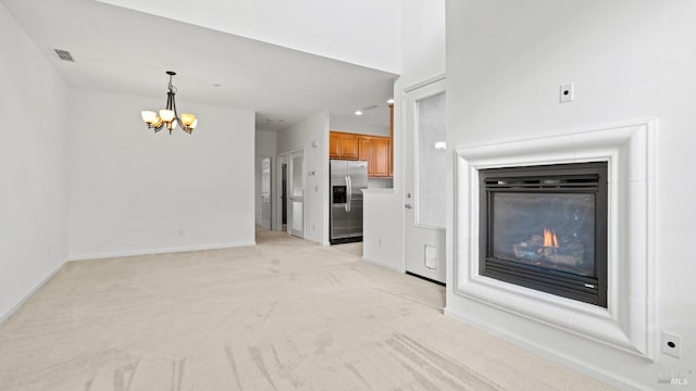 unfurnished living room featuring an inviting chandelier and light colored carpet