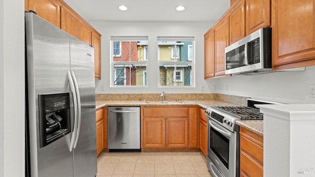 kitchen featuring light stone counters, sink, light tile patterned flooring, and appliances with stainless steel finishes