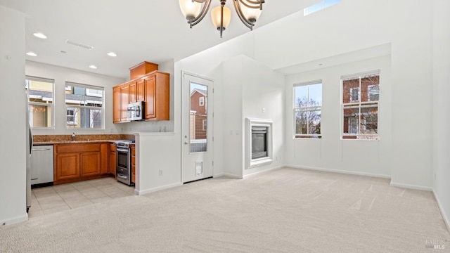 kitchen featuring sink, an inviting chandelier, appliances with stainless steel finishes, a wealth of natural light, and light colored carpet