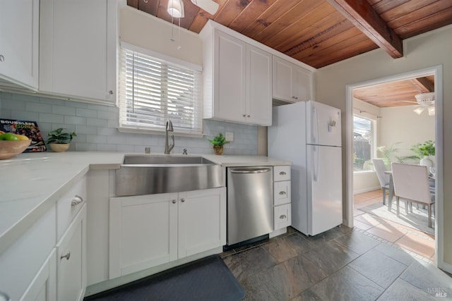 kitchen featuring stainless steel dishwasher, a ceiling fan, freestanding refrigerator, and a sink