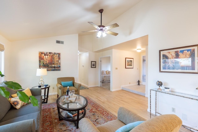 living area with baseboards, visible vents, a ceiling fan, light wood-style floors, and high vaulted ceiling