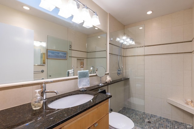 full bath featuring toilet, decorative backsplash, tiled shower, and vanity