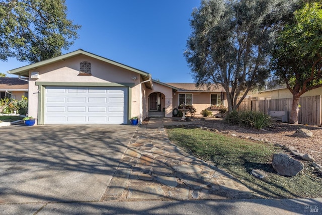 ranch-style house featuring driveway, an attached garage, fence, and stucco siding