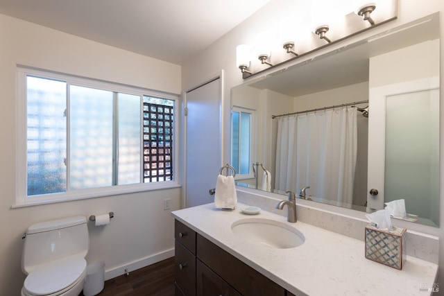 bathroom with wood finished floors, vanity, toilet, and baseboards